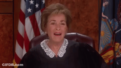 A Judge Is Sitting In Front Of An American Flag And Smiling . GIF