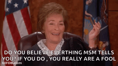 A Judge Is Smiling In Front Of An American Flag While Sitting In A Chair . GIF