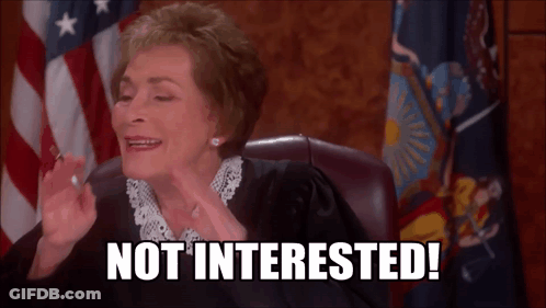 A Judge Sitting In Front Of An American Flag With The Words Not Interested On Her Face GIF