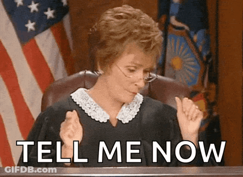 A Judge Sitting In Front Of An American Flag With The Words Tell Me Now Written Below Her GIF