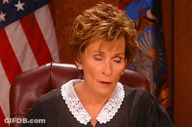 A Judge With Her Eyes Closed Is Sitting In Front Of An American Flag . GIF