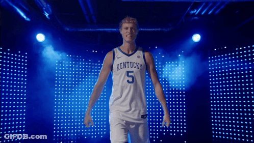 A Kentucky Basketball Player Stands In Front Of A Blue Backdrop GIF
