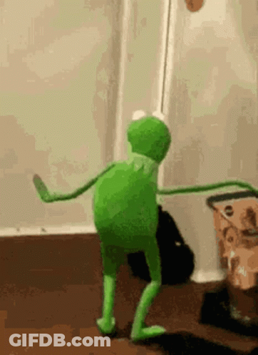 A Kermit The Frog Is Dancing In A Room In Front Of A Door . GIF