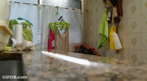 A Kitchen With Clothes Hanging On A Clothes Line GIF