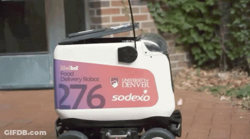 A Kiwibot Food Delivery Robot Is Parked In Front Of A Building GIF