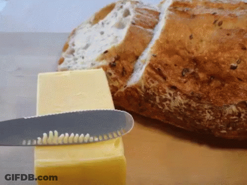 A Knife Is Cutting A Piece Of Butter Next To A Slice Of Bread GIF
