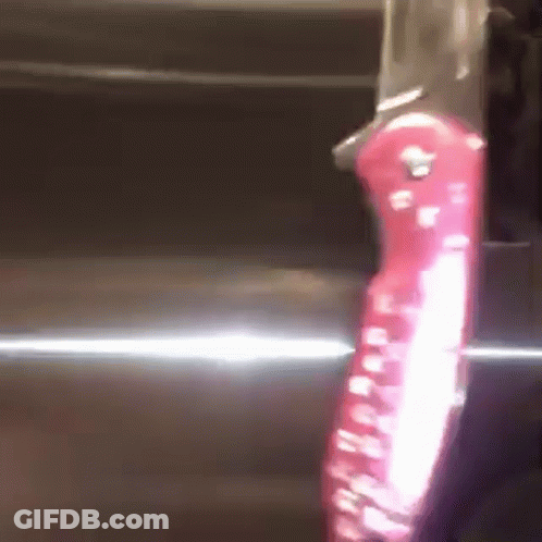 A Knife With A Red Handle Is On A Shiny Surface GIF