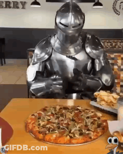 A Knight In Armor Is Sitting At A Table With A Pizza GIF