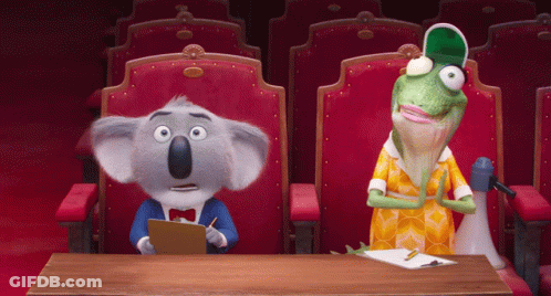 A Koala Bear And A Lizard Sit At A Table In A Theater GIF