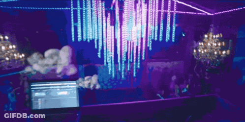 A Laptop Is On A Table In Front Of A Purple Chandelier GIF