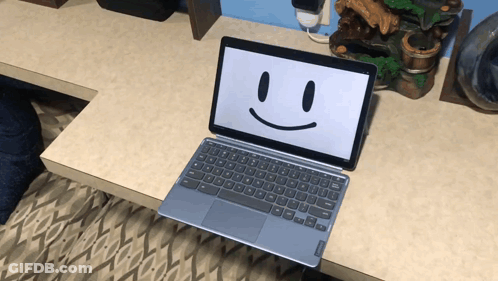 A Laptop With A Smiley Face On The Screen Sits On A Desk GIF