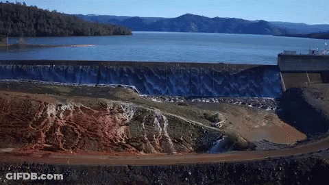 A Large Body Of Water With Mountains In The Background And A Dam In The Foreground GIF
