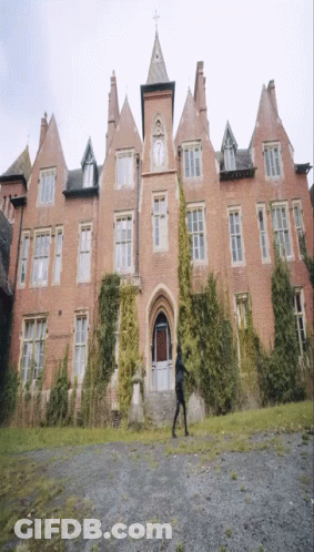 A Large Brick Building With A Clock On The Front GIF
