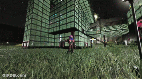 A Large Building With A Lot Of Windows Is Lit Up At Night And A Person Is Standing In Front Of It GIF