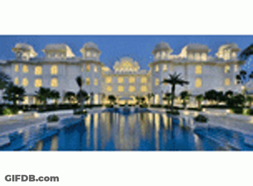 A Large Building With A Swimming Pool In Front Of It GIF