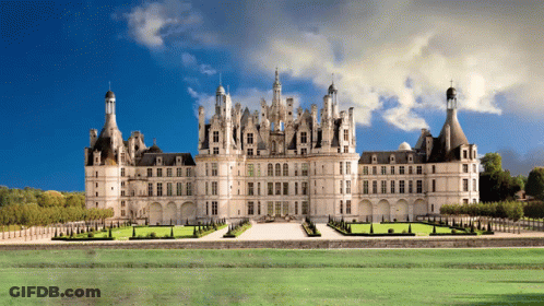 A Large Castle Sits In The Middle Of A Grassy Field GIF