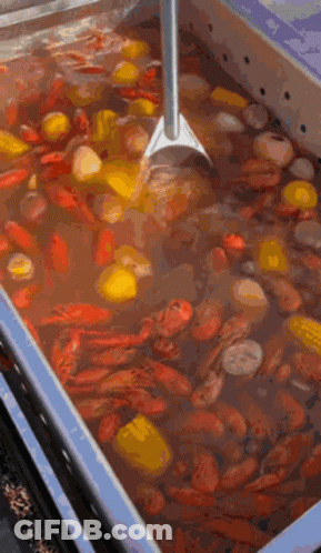 A Large Container Filled With Crawfish , Corn , Potatoes , And A Shovel . GIF