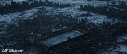 A Large Crowd Of People Are Gathered Around A Large Building In The Middle Of A Snowy Field GIF