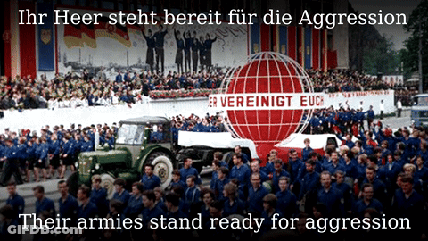 A Large Crowd Of People Are Gathered In Front Of A Sign That Says " Ihr Heer Steht Bereit Für Die Aggression " GIF