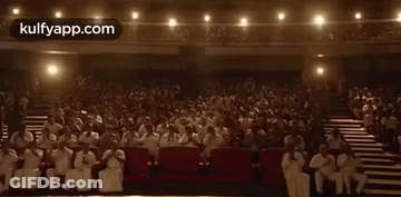 A Large Crowd Of People Are Sitting In A Theater . GIF