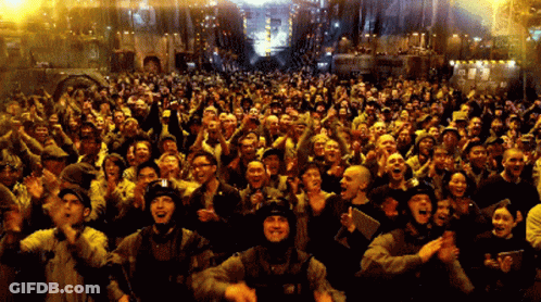 A Large Crowd Of People Are Standing In Front Of A Building That Says ' A ' On It GIF