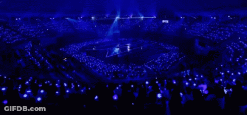 A Large Crowd Of People Are Watching A Concert In A Stadium With Blue Lights GIF