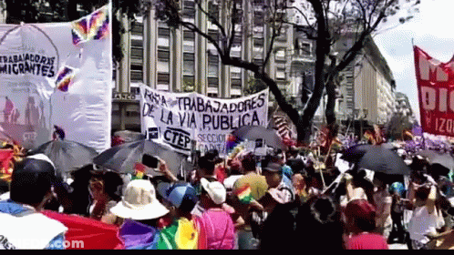 A Large Crowd Of People Holding Umbrellas And A Sign That Says Trabajadores De La Via Publica GIF