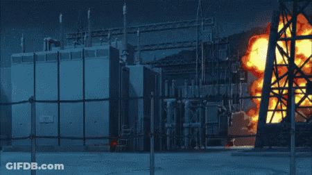 A Large Fire Is Coming Out Of A Building With A Fence In The Foreground . GIF