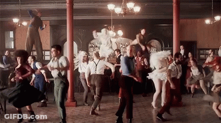 A Large Group Of People Are Dancing In A Room In A Circus . GIF