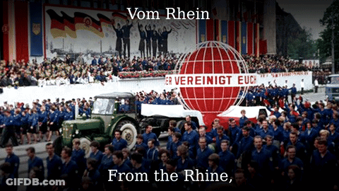A Large Group Of People Are Gathered In Front Of A Sign That Says Vom Rhein From The Rhine GIF