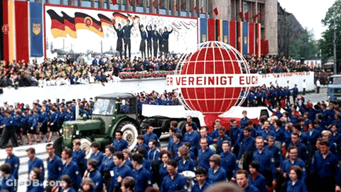 A Large Group Of People Are Marching In Front Of A Sign That Says " Er Vereinigt Euc " GIF