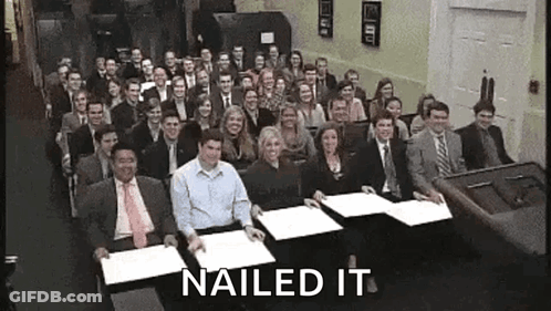 A Large Group Of People Are Sitting At Tables With Papers In Front Of Them And The Words Nailed It Are Above Them . GIF