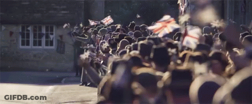 A Large Group Of People Are Standing In Front Of A Building GIF