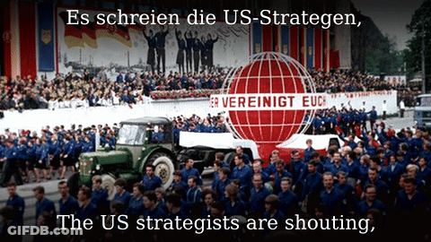 A Large Group Of People Marching In Front Of A Sign That Says Vereinigt Euc GIF