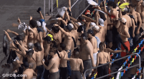 A Large Group Of People Without Shirts Are Gathered In A Stadium GIF