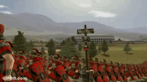 A Large Group Of Roman Soldiers Marching In A Field With Mountains In The Background GIF