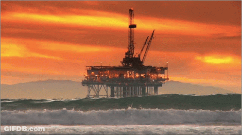A Large Oil Rig In The Middle Of The Ocean With A Sunset In The Background GIF