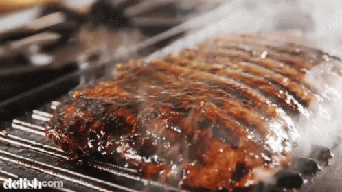 A Large Piece Of Meat Is Cooking On A Grill And The Word Delish Is Visible In The Corner GIF