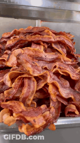 A Large Pile Of Bacon Is Sitting On A Tray GIF