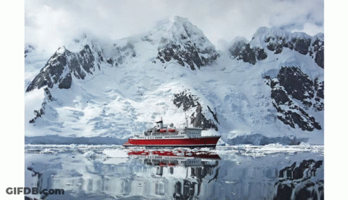 A Large Red Ship Is Floating In The Water In Front Of Snow Covered Mountains GIF