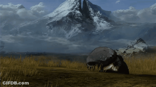 A Large Rock In The Middle Of A Field With A Mountain In The Background GIF