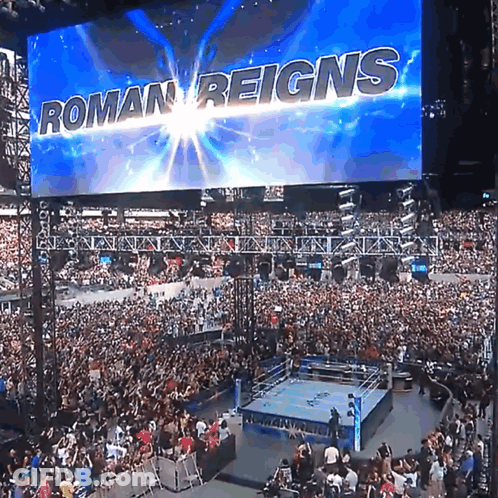 A Large Screen Says Roman Reigns Over A Crowd GIF