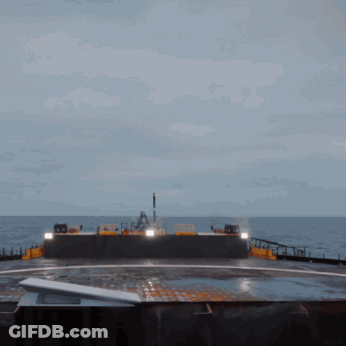 A Large Ship Is In The Middle Of The Ocean With A Few Lights On The Side GIF
