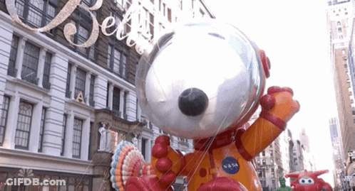 A Large Snoopy Balloon Is In Front Of A Building That Says Nbc On It GIF