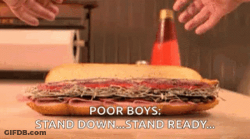 A Large Sub Sandwich Is Sitting On A Wooden Table With The Words `` Poor Boys : Stand Down ... Stand Ready ... '' GIF