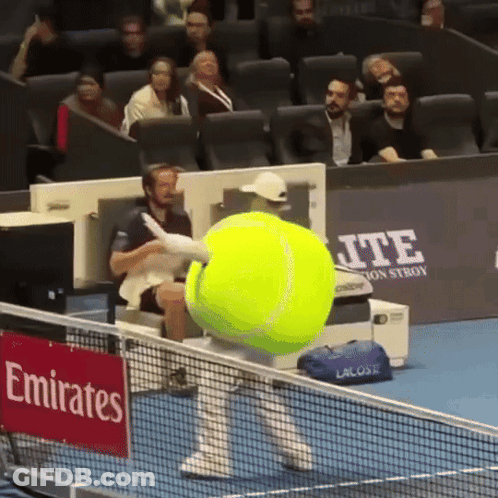 A Large Tennis Ball Is Being Thrown On A Tennis Court With A Sign That Says Emirates On It GIF