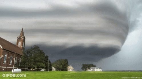 A Large Tornado Is Moving Over A Church And A Field GIF