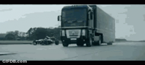 A Large Truck Is Driving Down A Road With A Motorcycle In The Background . GIF