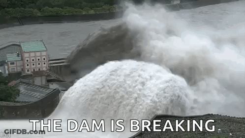 A Large Waterfall Is Coming Down A Dam With The Words `` The Dam Is Breaking '' Written Below It . GIF