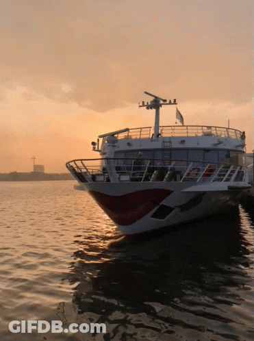 A Large White And Red Boat Is Docked In The Water At Sunset GIF
